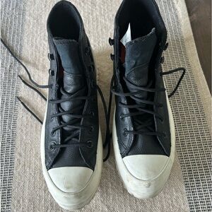 Chuck Taylor leather all black with white soles. Water proof.